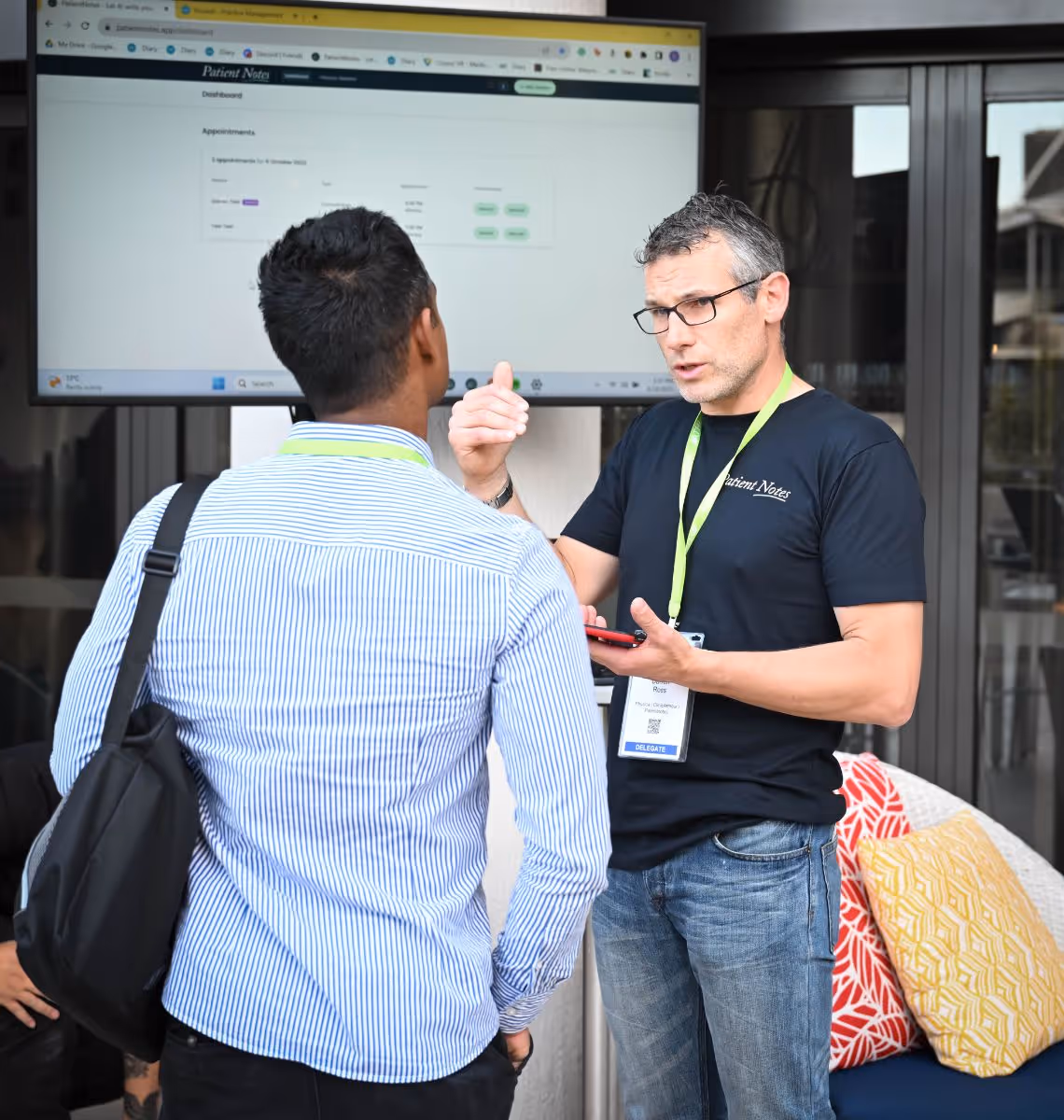A man in a blue striped shirt is talking to a man in a black shirt.