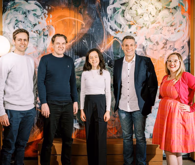 A group of people standing in front of a painting.